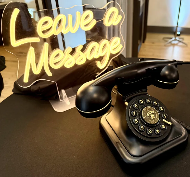 Audio guest book rental for weddings, a vintage black telephone with a Leave a Message neon sign at a SwissMixx Audio reception