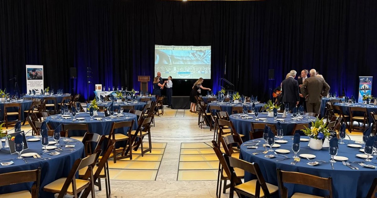 Gala tables set in the Utah State Capitol rotunda before doors, stage and screen ready at the far end