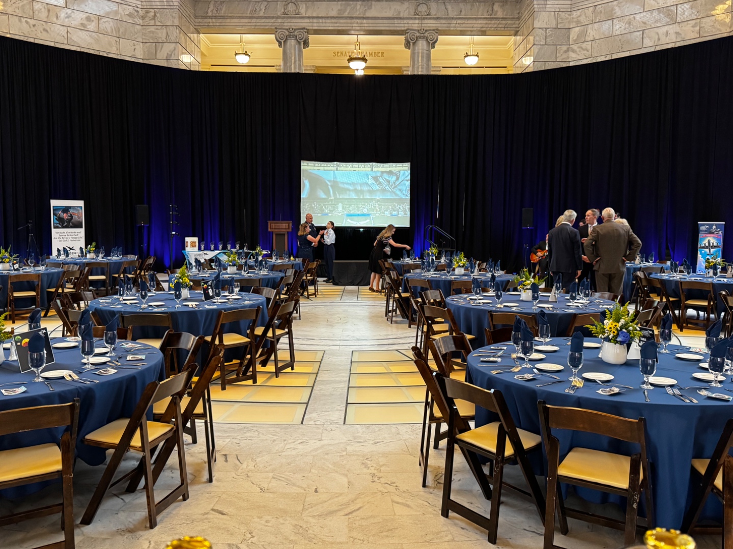 Corporate event setup in Utah State Capitol Senate Chamber with round tables, projection screen, and professional AV by SwissMixx Audio