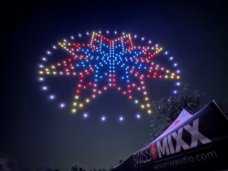 Drone light show star formation above the SwissMixx Audio banner at a Utah night show with synchronized audio
