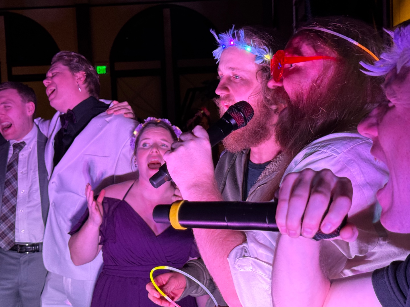 Guests belting into microphones at a SwissMixx Audio karaoke event with LED props and colored lighting