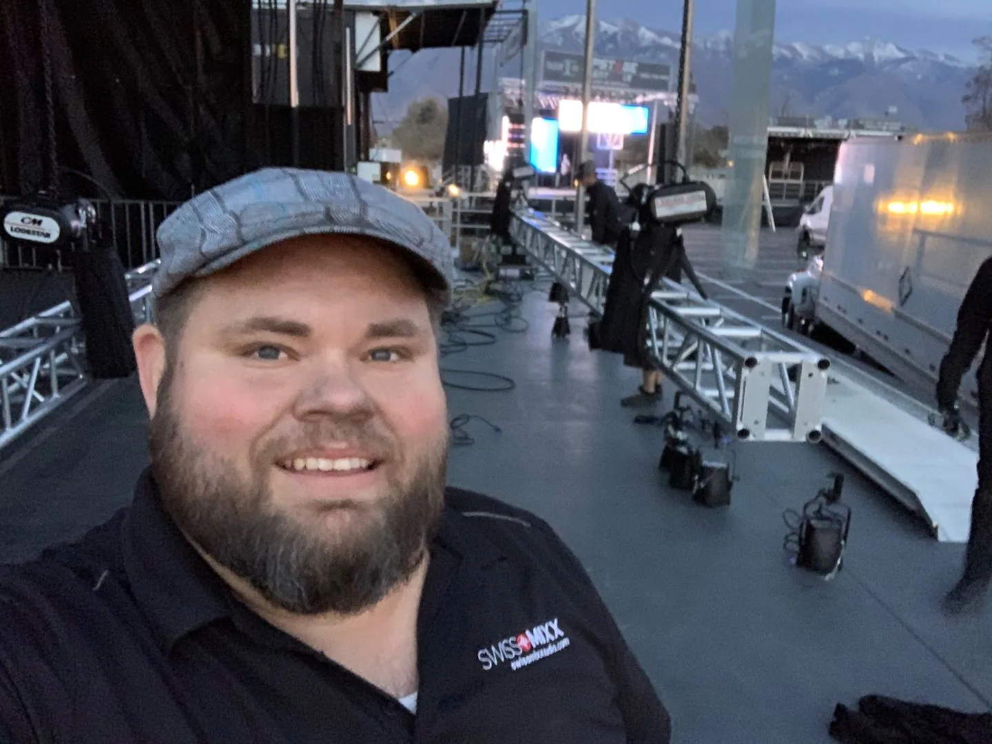 Mark Christiansen during a stadium load-in with staging trusses and mountains behind