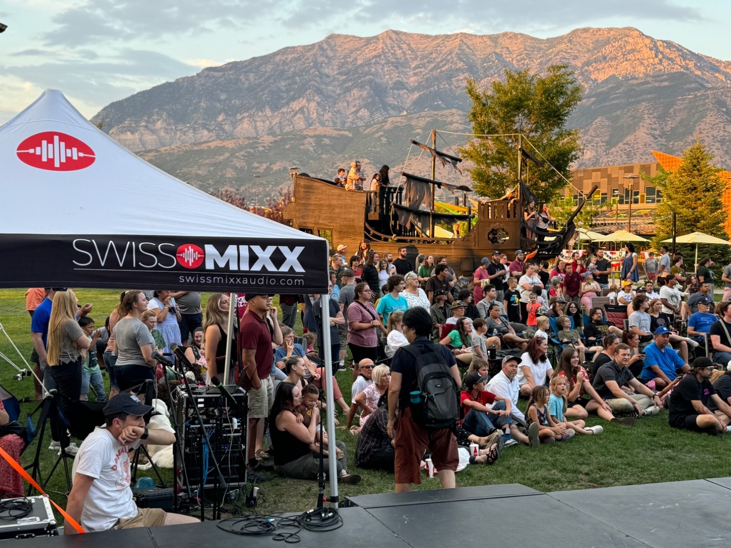 SwissMixx Audio tent at a community outdoor festival with mountains in the background and a large crowd
