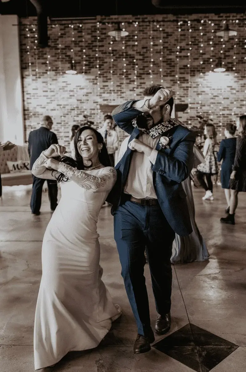 Couple dipping on the dance floor under string lights at their wedding reception
