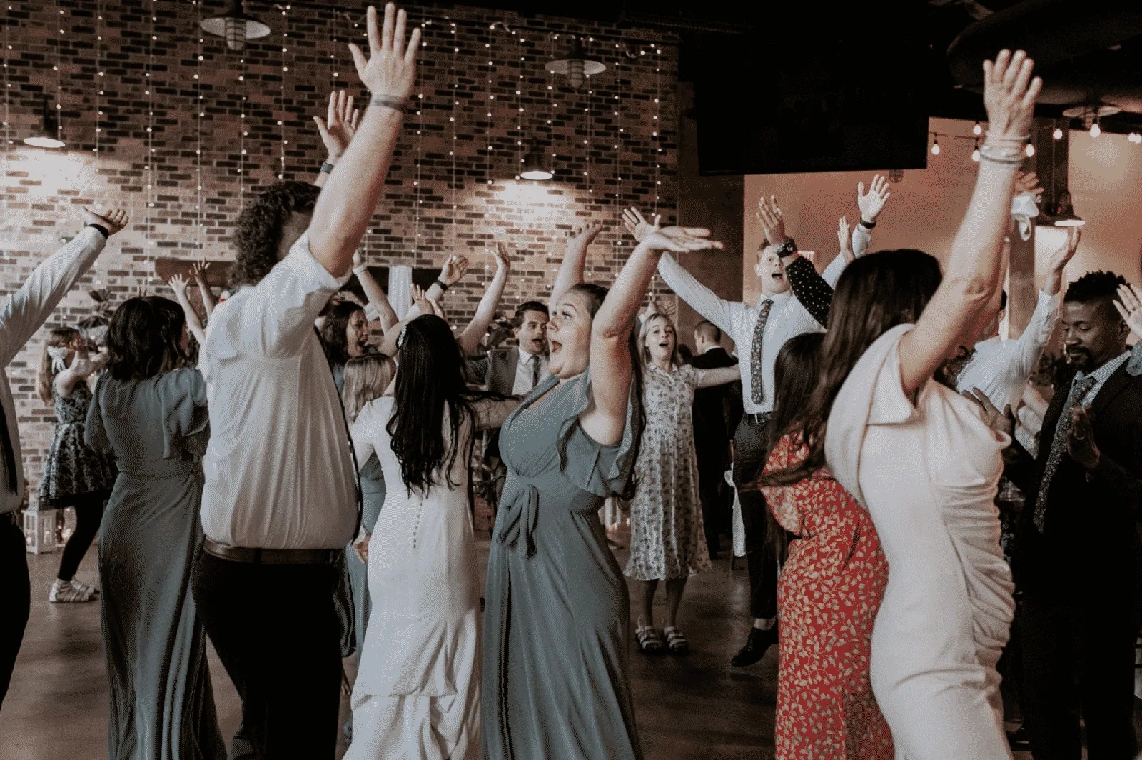 Wedding guests with hands raised on a packed dance floor